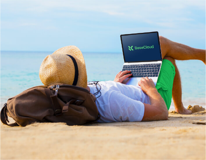 Person comfortably laying on beach, typing on laptop